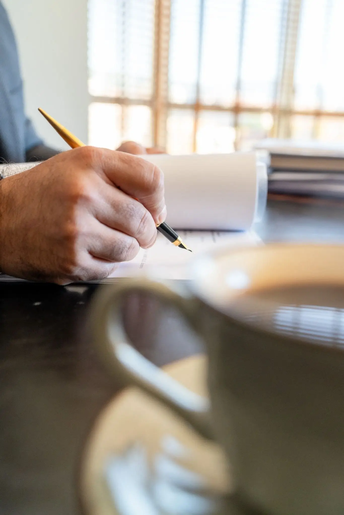Belge üzerinde çalışan avukat eli ve kalem detayı – Özbek Hukuk Bürosu