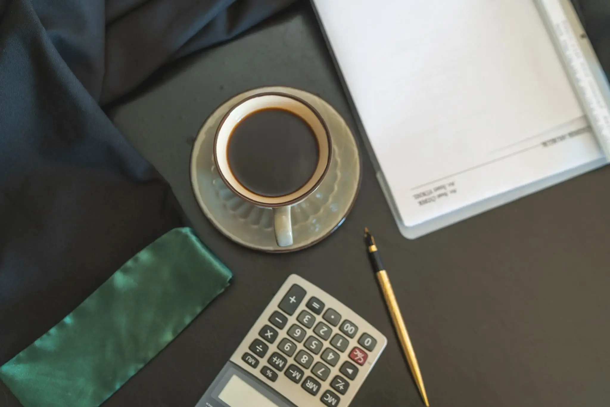 Avukat masa üstünde kahve, cübbe, kalem, hesap makinesi ve evrak detay fotoğrafı – Özbek Hukuk Bürosu